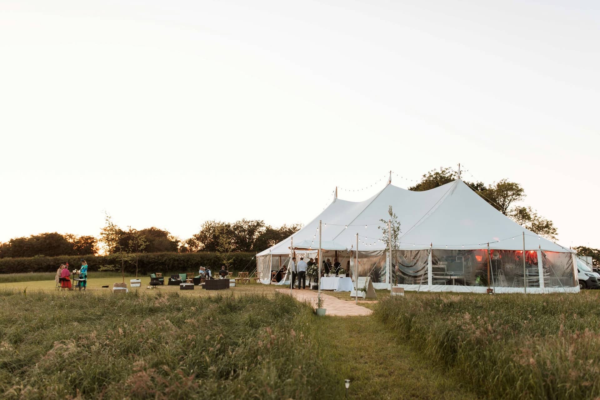 Willow wedding marquee package for Yorkshire weddings, A Large white event tent set up on a grassy field with guests mingling outside and string lights overhead, wedding marquee hire Bedale